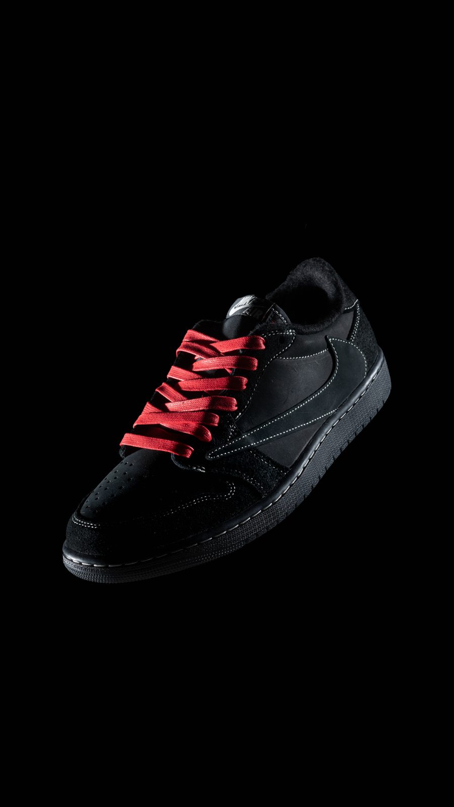 Still life di una sneaker nera sospesa su fondo nero
